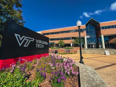 A Virginia Tech sign with Squires Student Center in the background.
