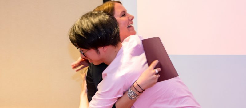 A female teacher hugging a male student
