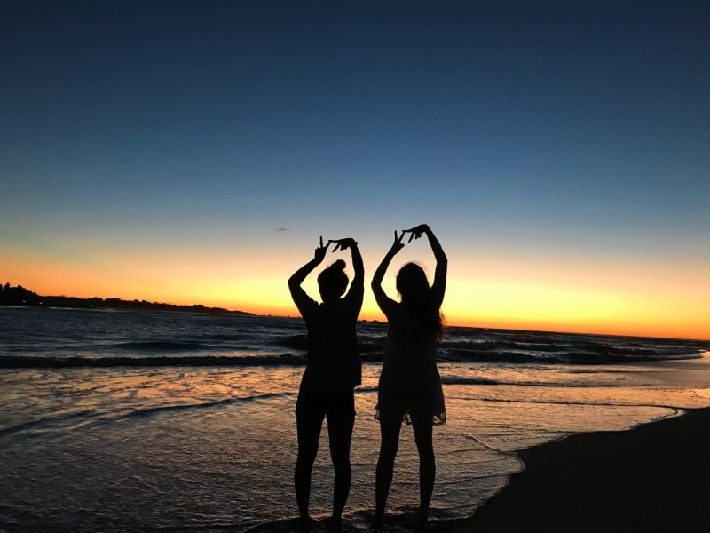 students in front of a sunset on a beach