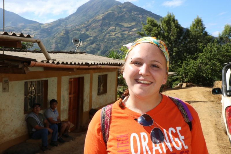 A student standing in front of a mountain house