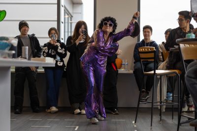 Woman dressed in sparkly purple jumpsuit dancing disco